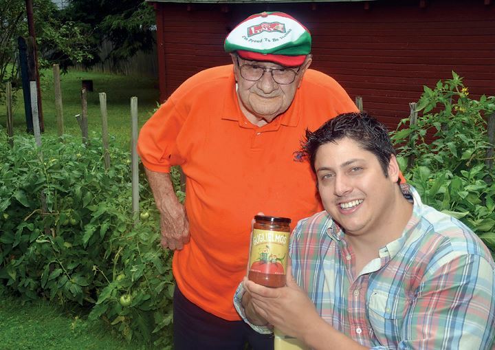 Grandpa Pete and Paul smiling in a garden, Paul holding a jar of sauce