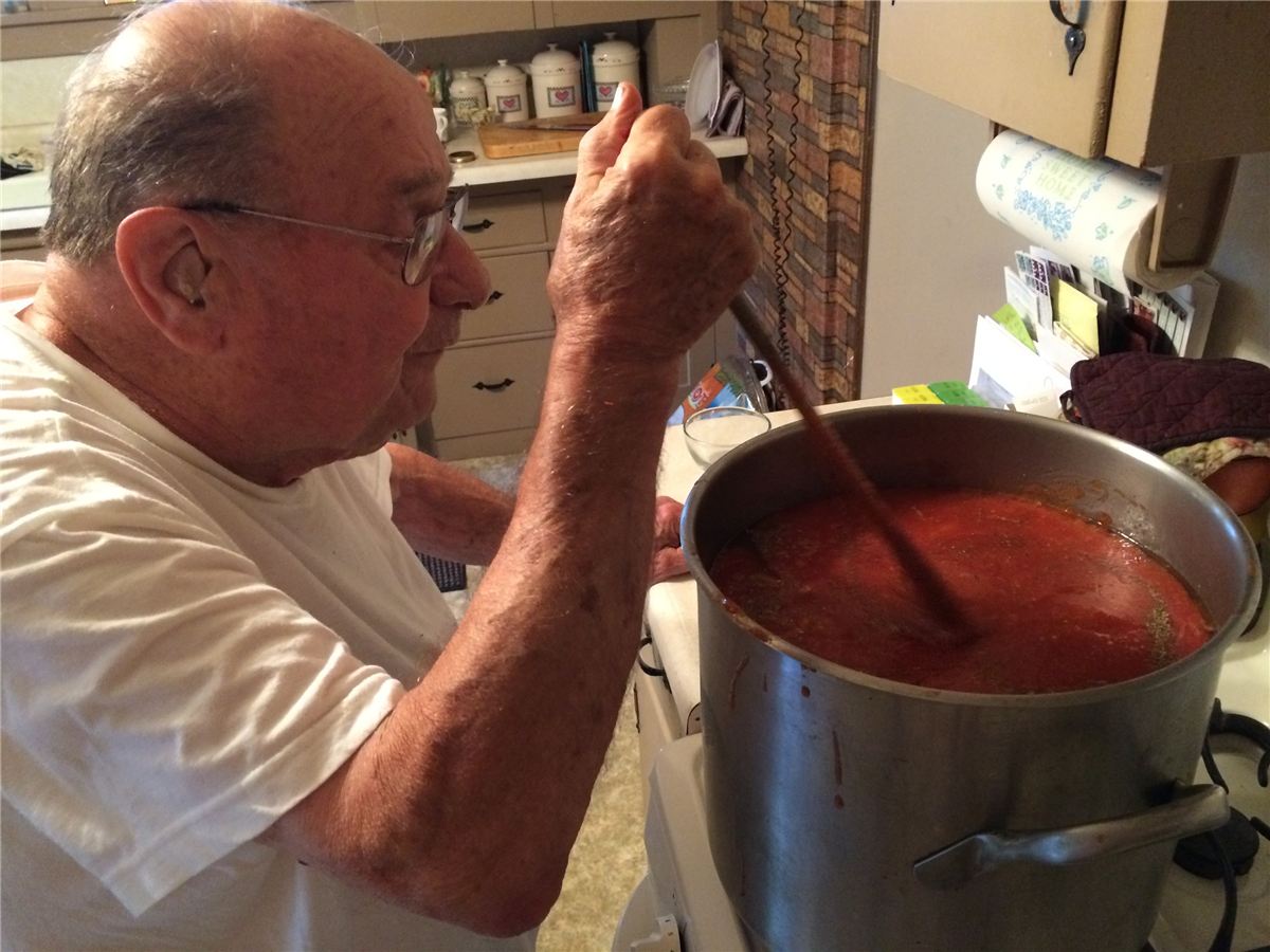Grandpa Pete stirring a large pot of tomato sauce